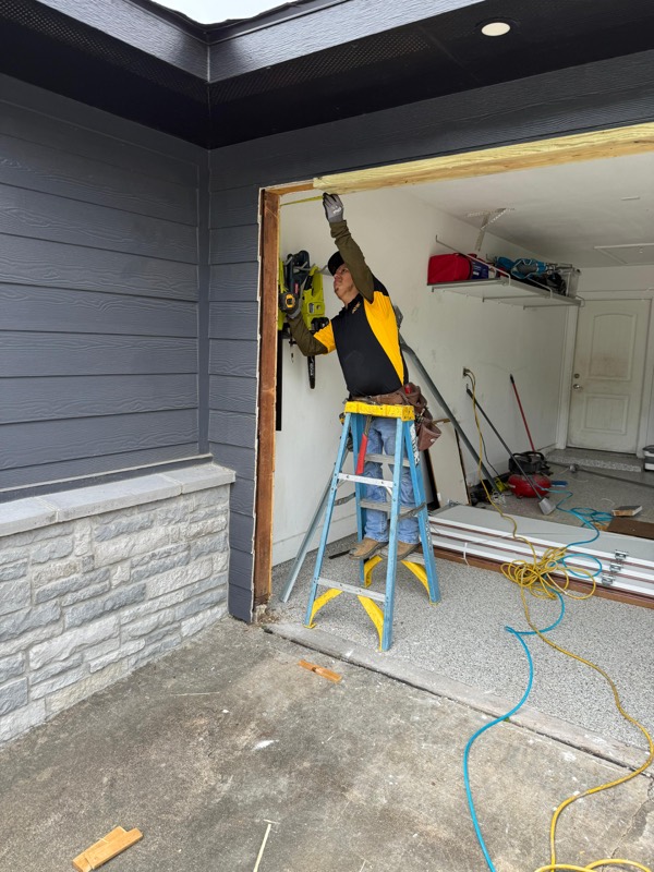 Tech installing a new garage door panel on a Houston home